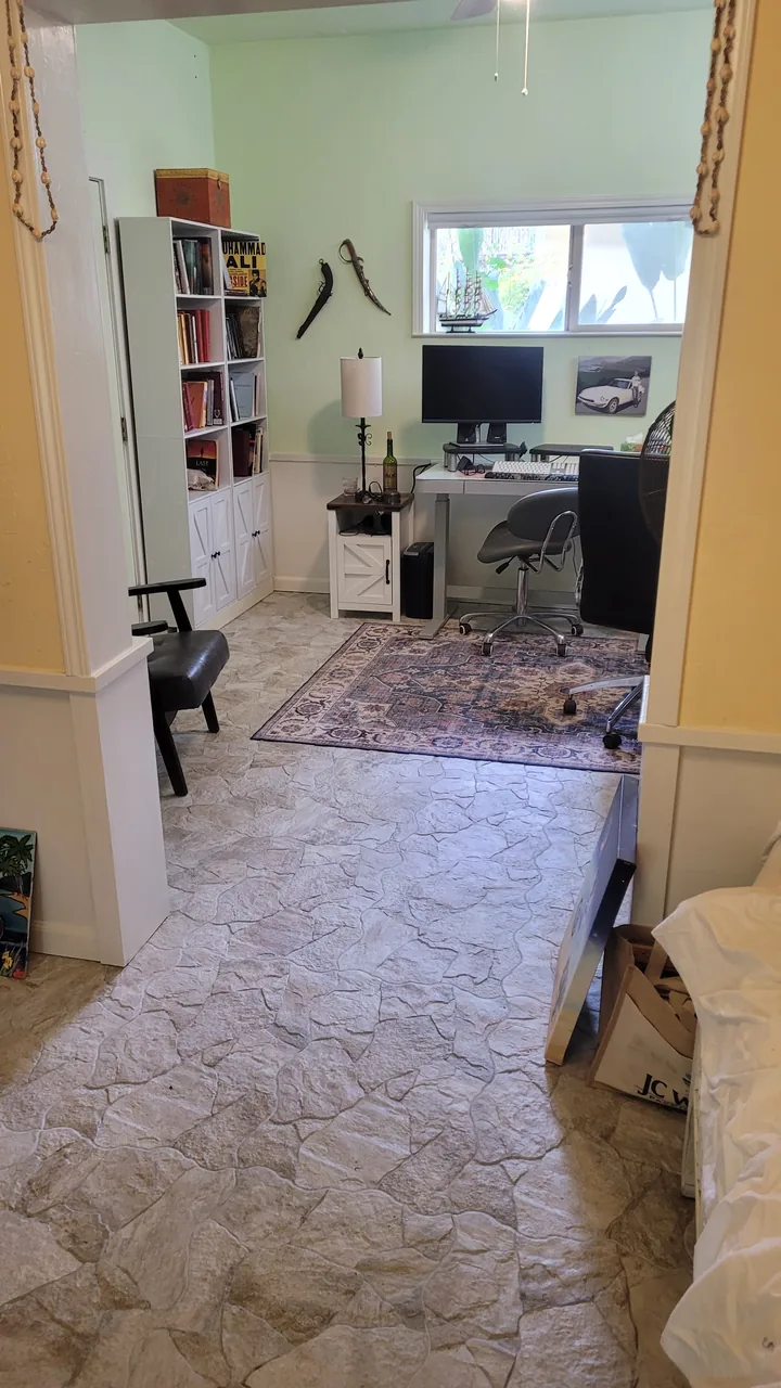 Finished basement office with a natural stone tile floor, painted walls and trim, and the owner's desk and computer.