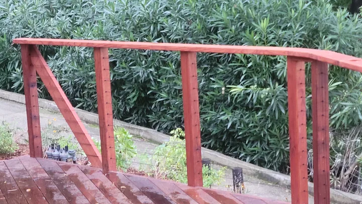 Close view of drilled railing posts, the top rail, and a diagonal wood brace before cabling.