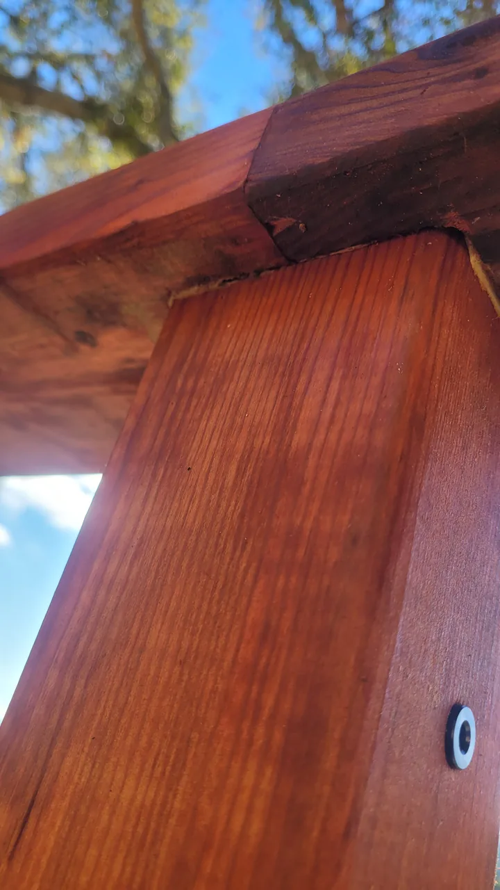 Close-up of a stained railing post meeting the underside of the top rail, with a recessed fastener visible.