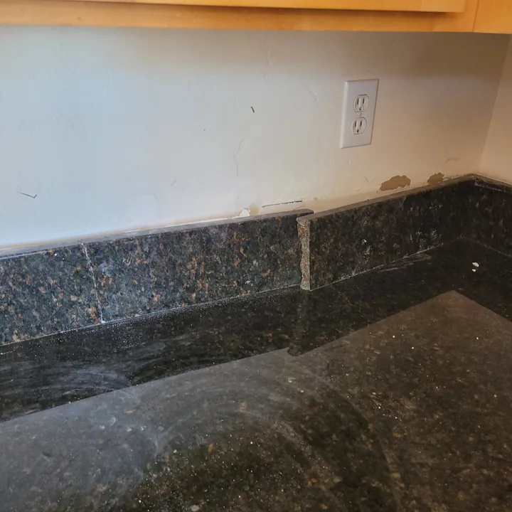 Visible break at the dark stone backsplash corner above the kitchen countertop.