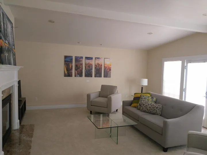 Vertical cityscape artworks arranged in a horizontal row above living-room seating, beside a large glass door.