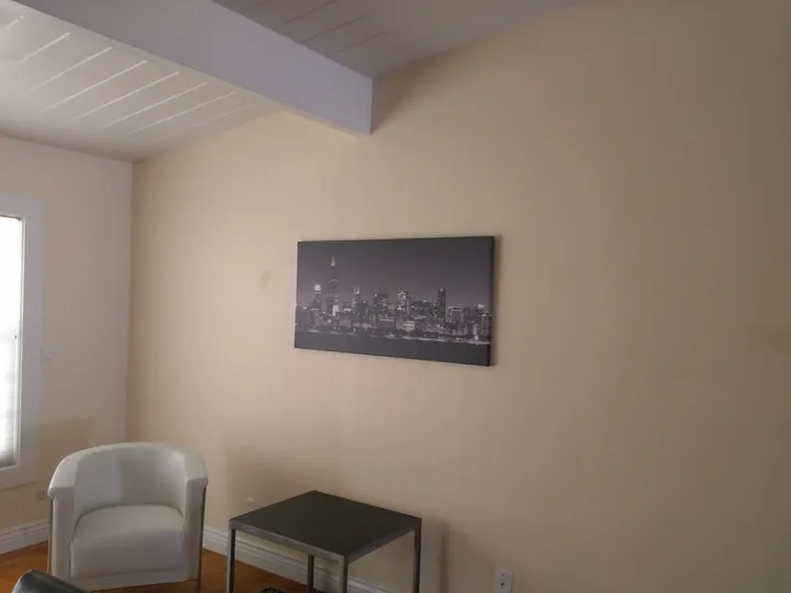 A single horizontal cityscape artwork above a small side table beside an upholstered chair.