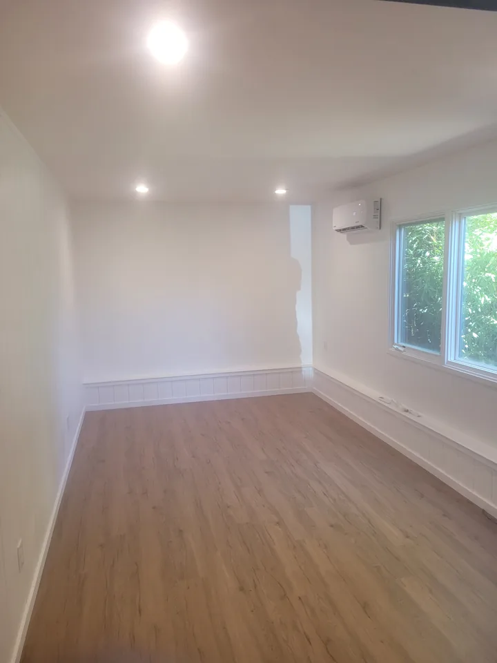 Finished room with plank flooring, white perimeter trim and recessed ceiling lights.